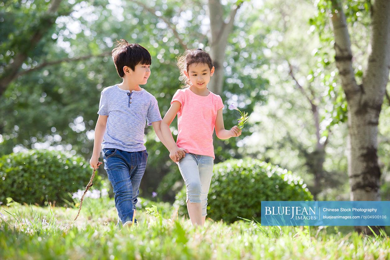 Happy Chinese children holding hands walking in woods