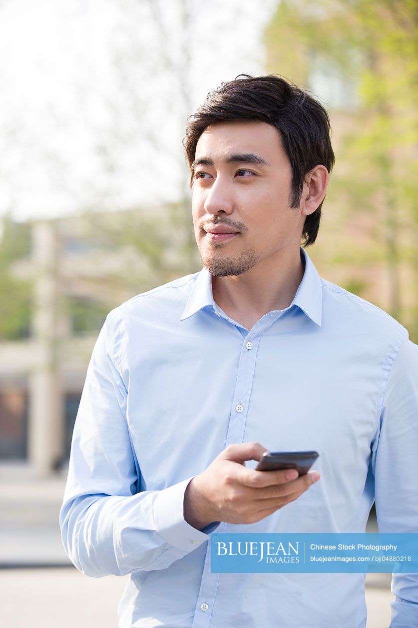 Young Chinese man holding a smart phone