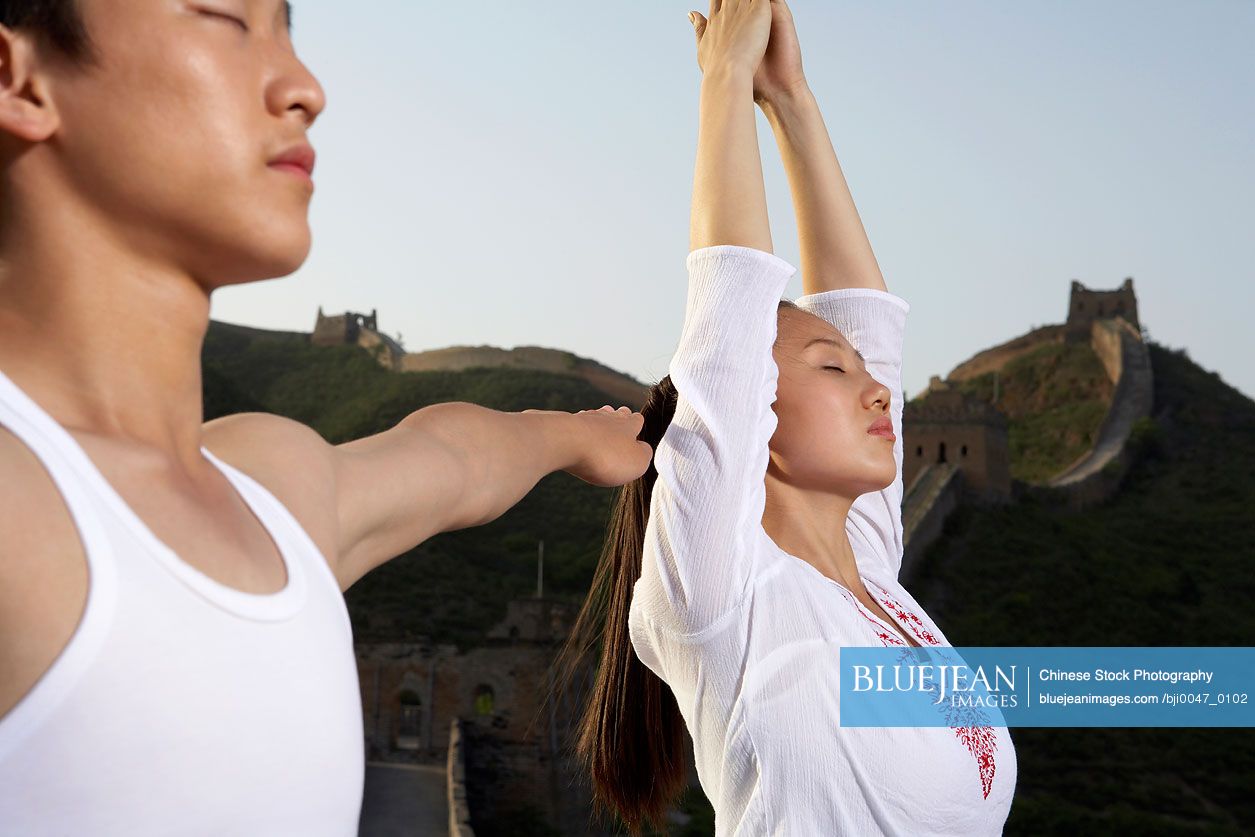 Chinese Woman And Chinese Man Doing Yoga On The Great Wall Of China