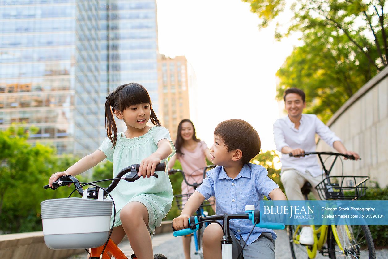 Happy young Chinese family riding bikes