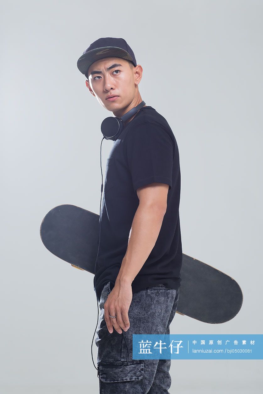 戴耳机的年轻男子手拿滑板