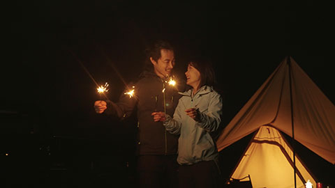 Happy Chinese couple holding sparklers and camping outdoors,4K