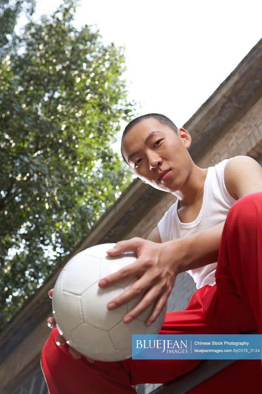 Chinese teenage boy holding soccer ball
