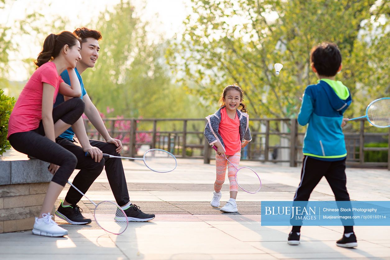 Happy young Chinese family playing badminton in park