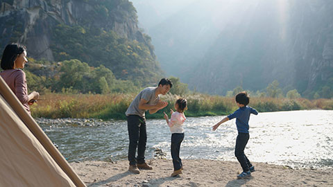 Happy young Chinese family camping outdoors