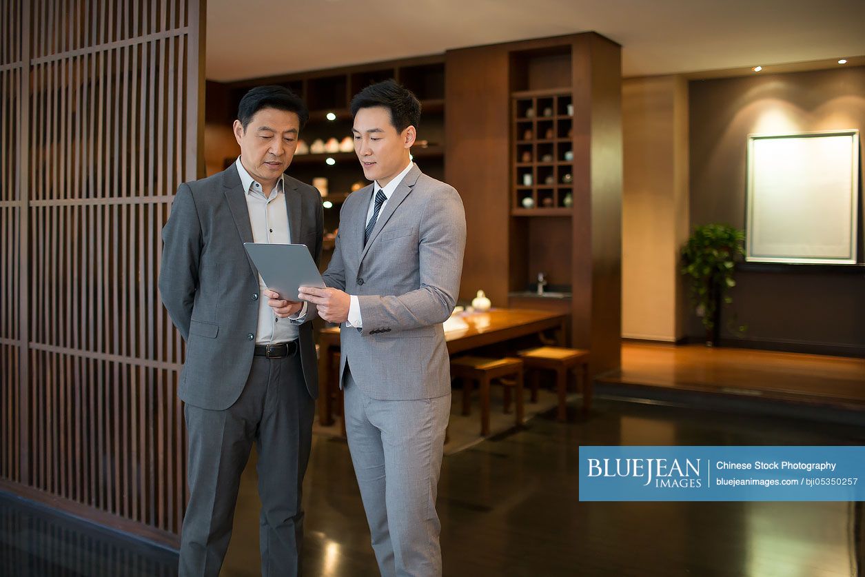 Cheerful Chinese businessmen using digital tablet