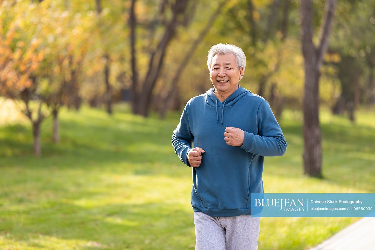 Happy senior Chinese man running in the park