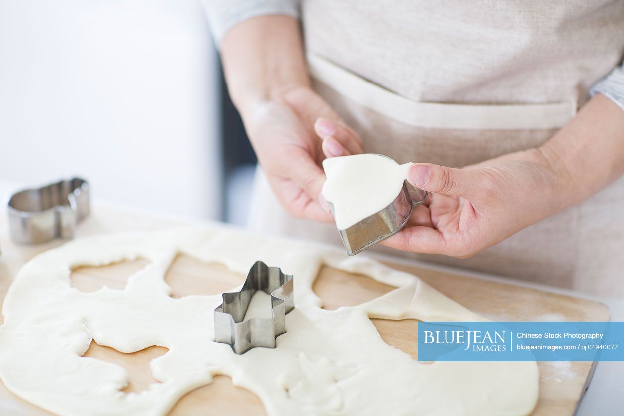 Young Chinese woman making cookies in kitchen