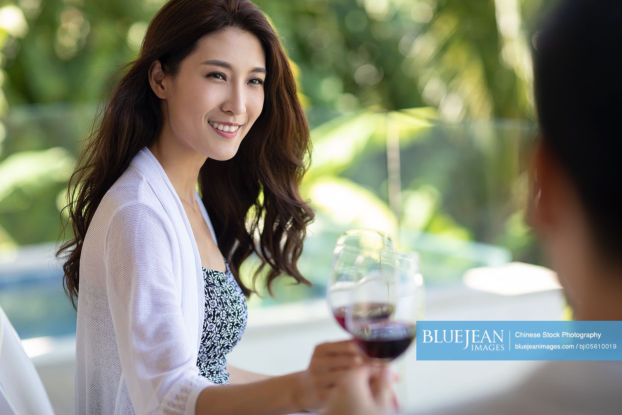 Happy young Chinese couple drinking wine on balcony