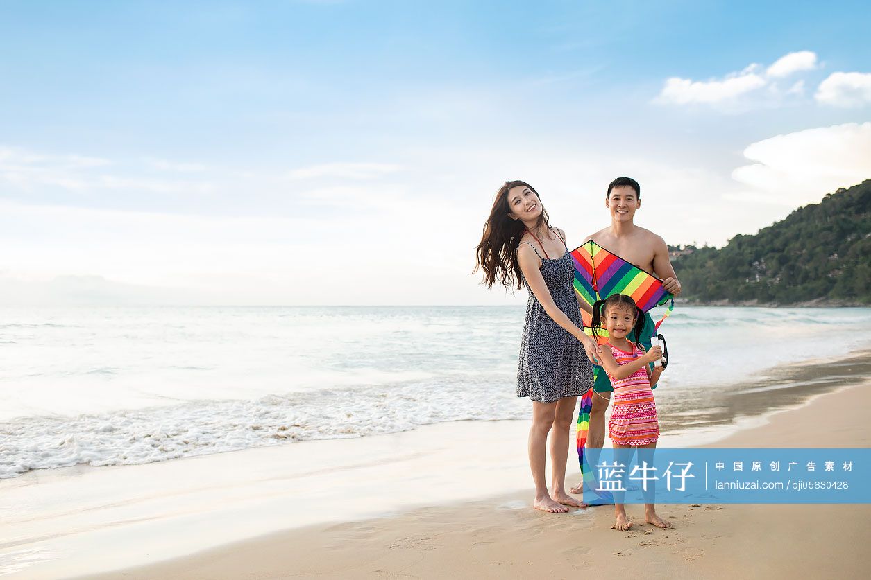 快乐的年轻家庭在沙滩放风筝