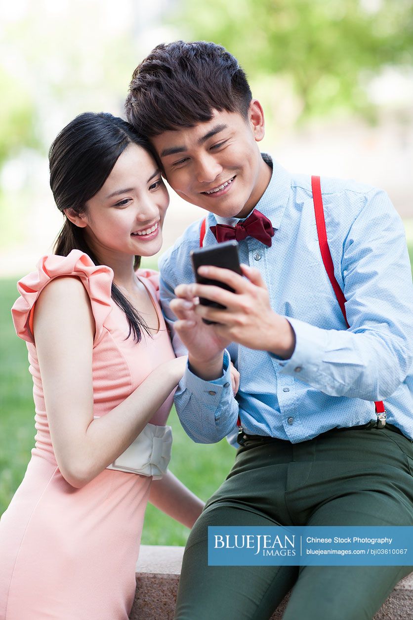 Stylish young Chinese couple with mobile phone
