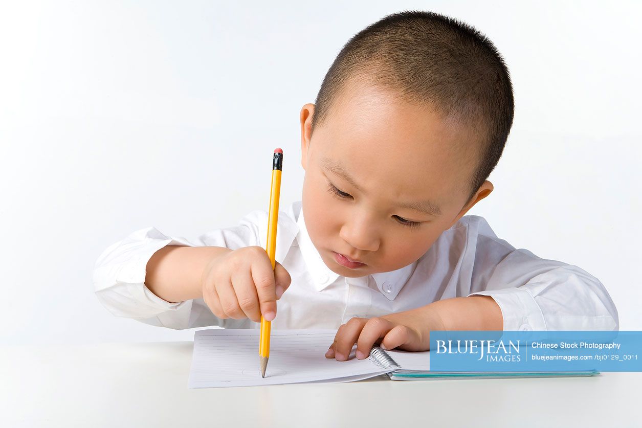 Young Chinese boy writes on a notebook