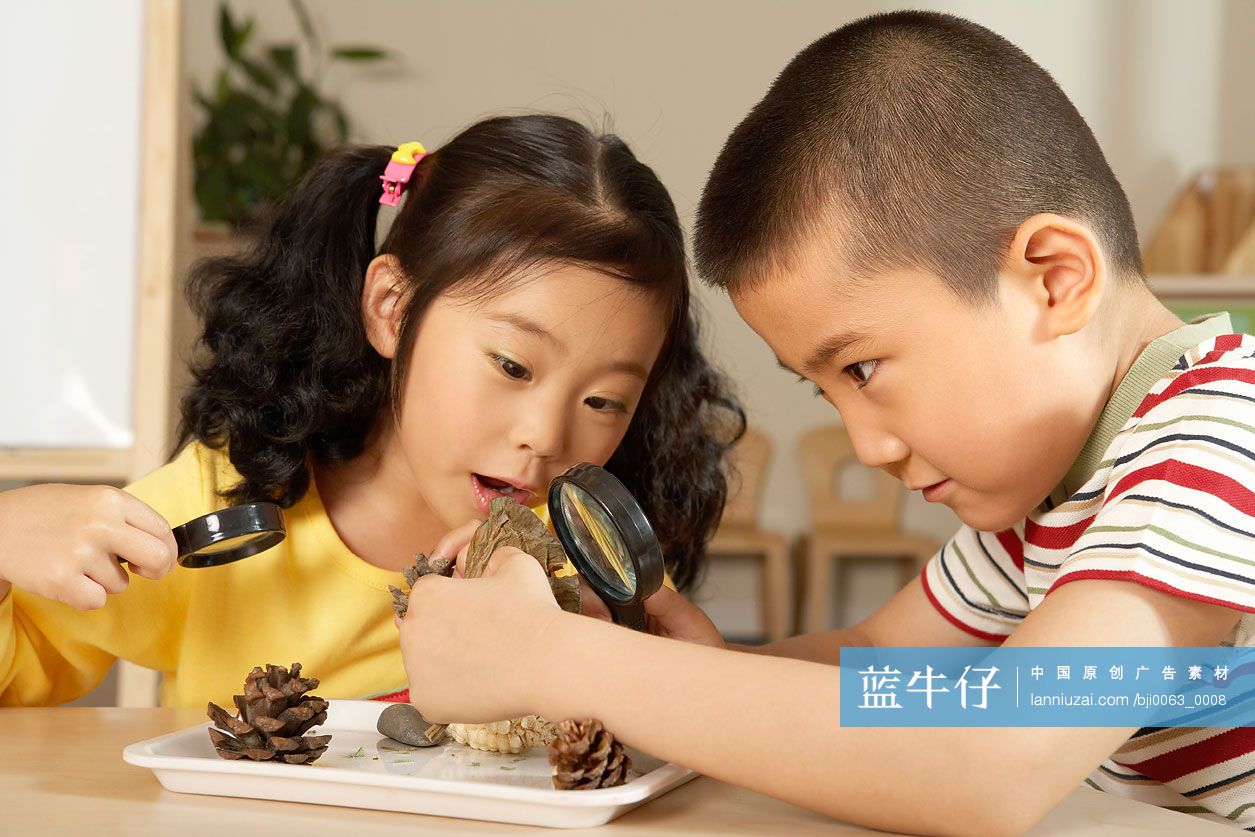 小女孩和小男孩用放大镜看物体