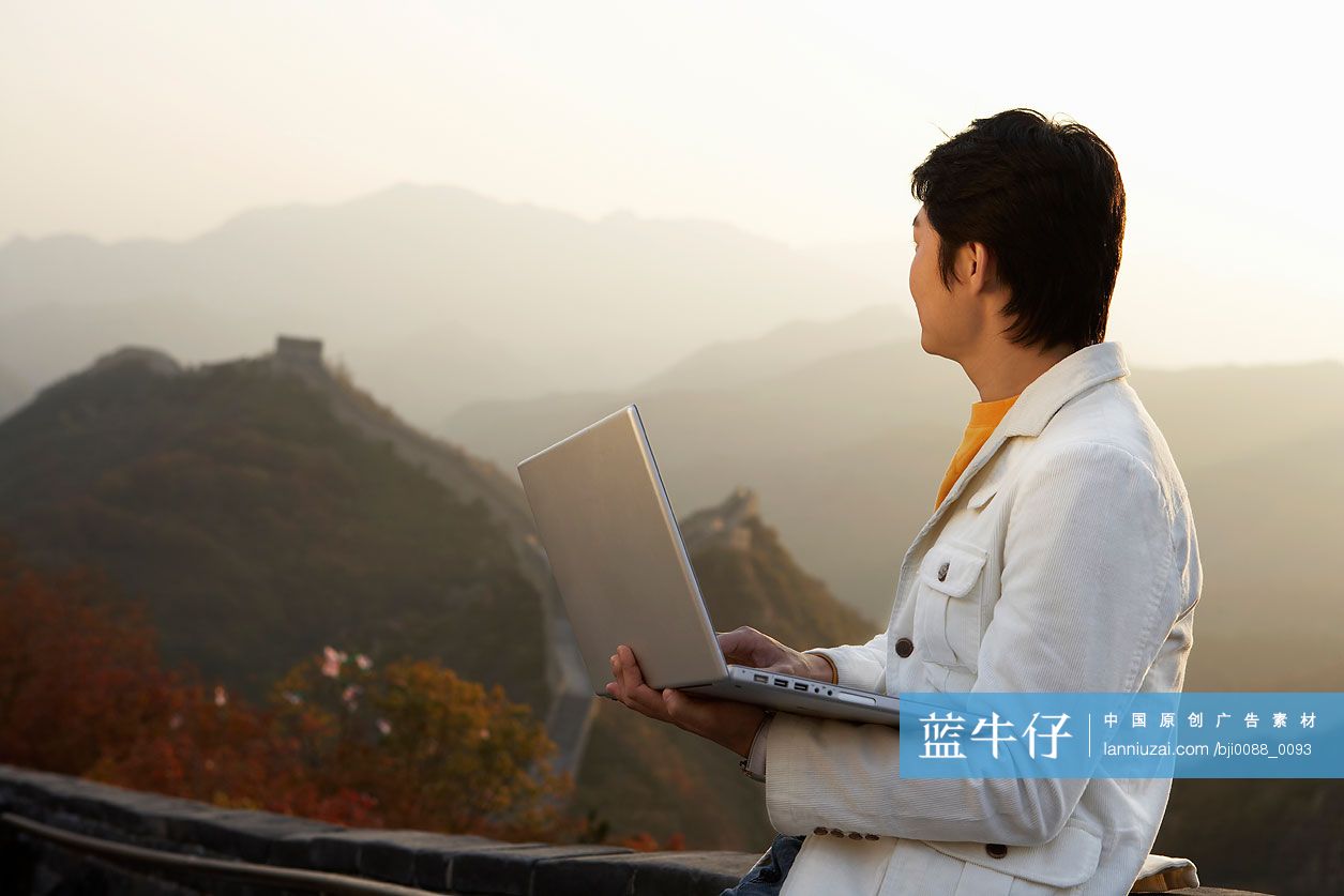 一位男孩正在长城上使用笔记本电脑