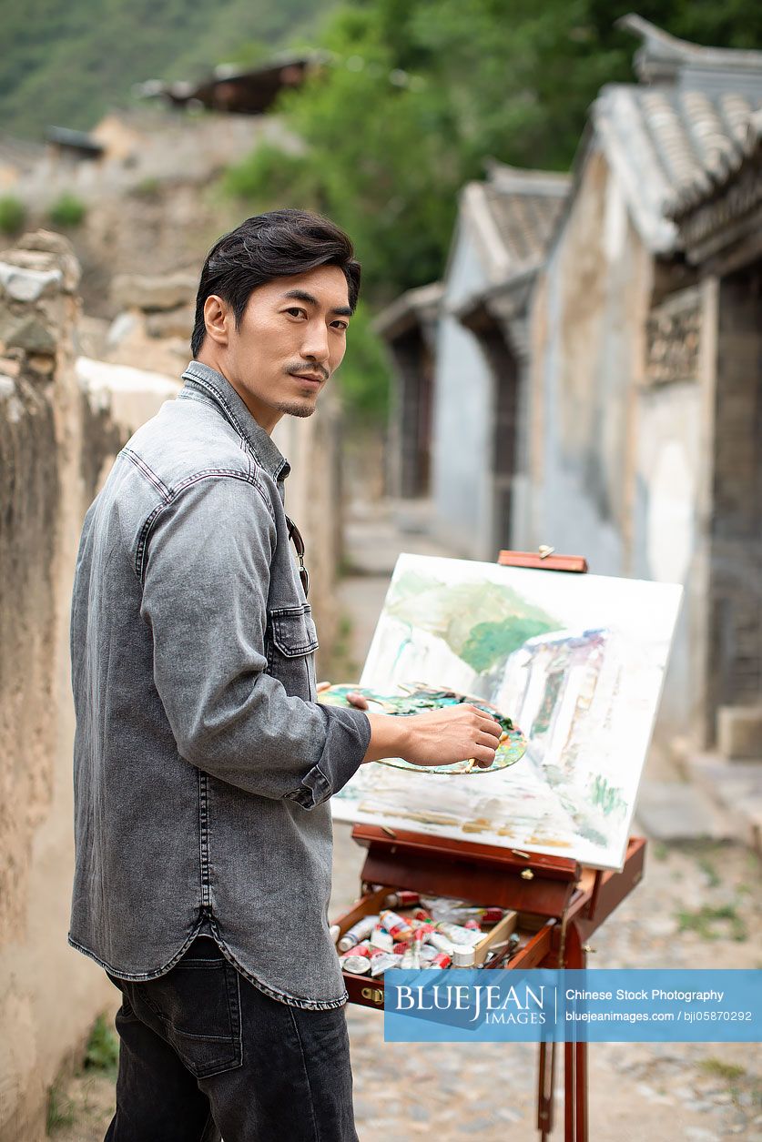 Young Chinese artist painting outdoors