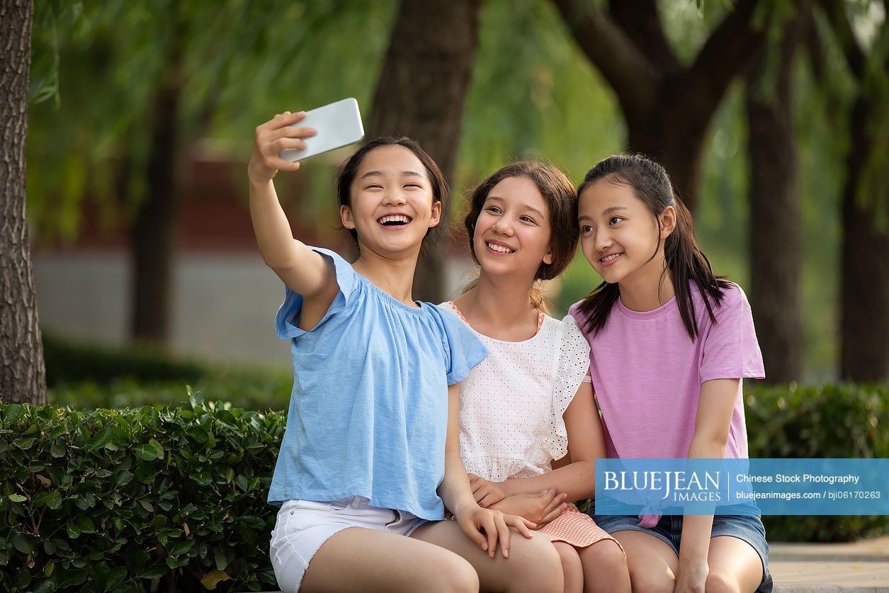 Teenager girls taking selfie with smartphone outdoors