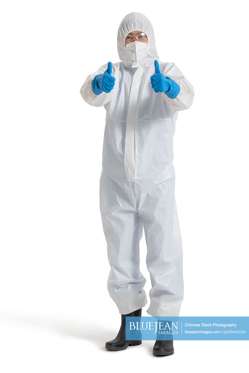 Young Chinese doctor in protective suit doing thumbs-up
