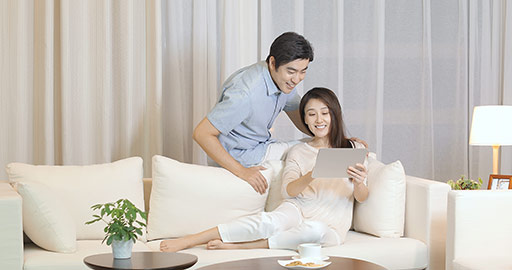 Happy young Chinese couple using digital tablet in living room,4K