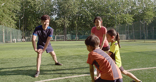 Happy young Chinese family warming up on soccer field,4K