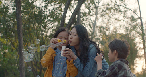 Happy young Chinese family blowing bubbles in park,4K