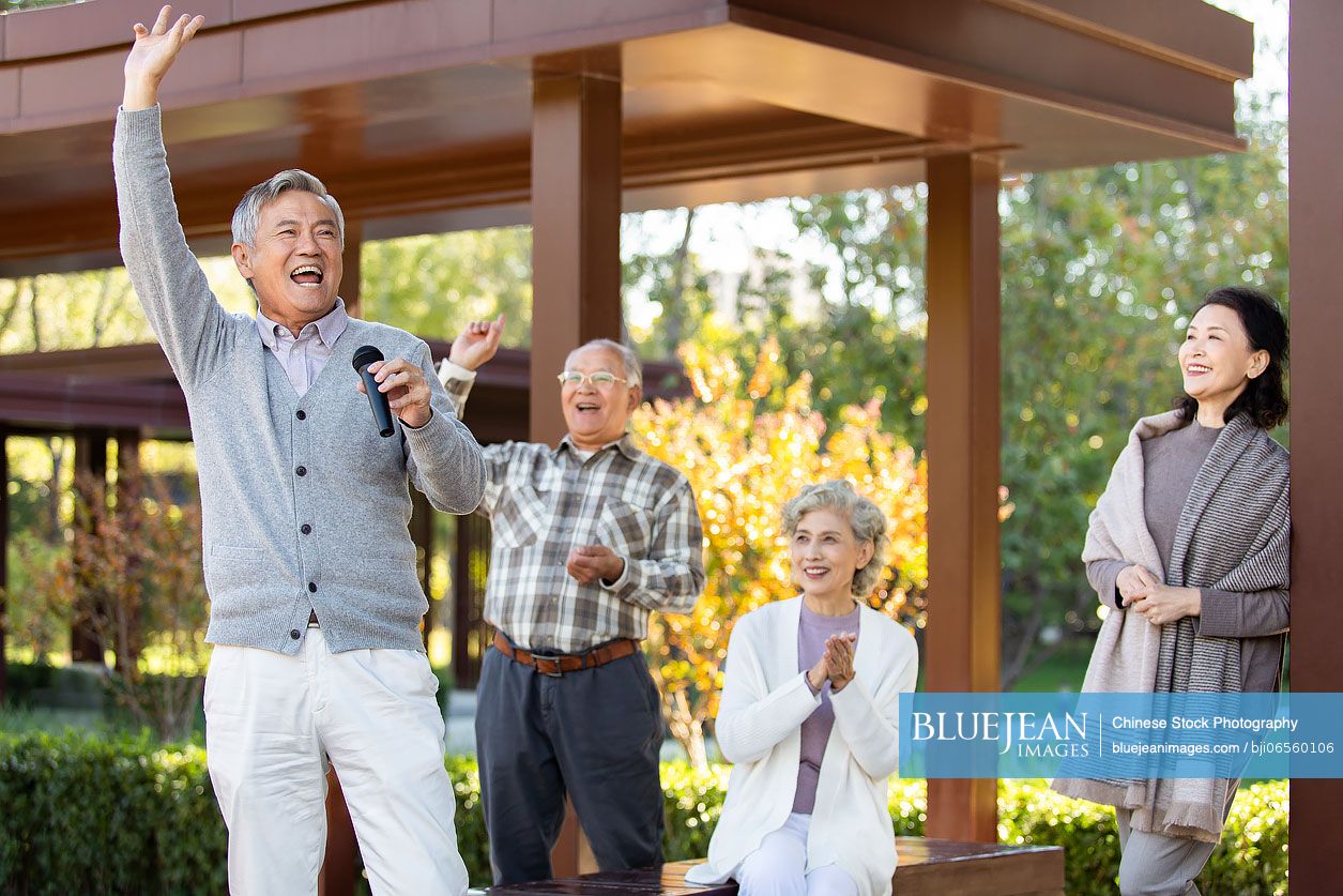 Cheerful senior Chinese man singing with microphone