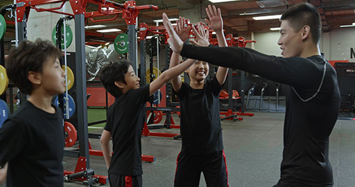 Cheerful Chinese children and coach high fiving in gym,4K