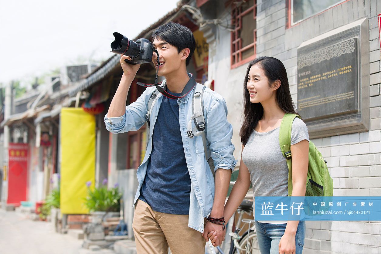 年轻情侣拿着相机在北京胡同里旅游
