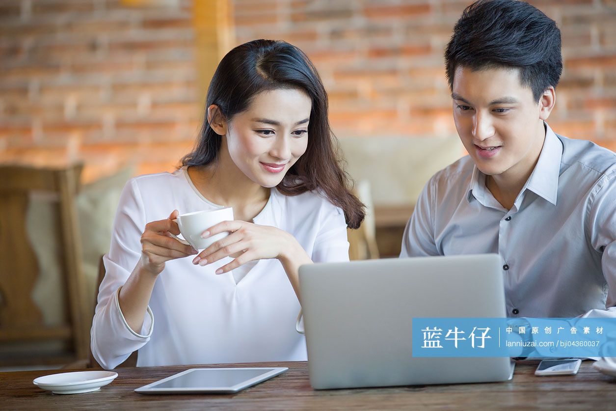 年轻男女在咖啡馆使用笔记本电脑