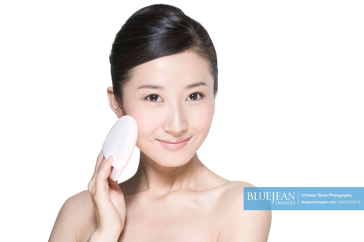 Beauty shot of a young Chinese woman holding a powder puff