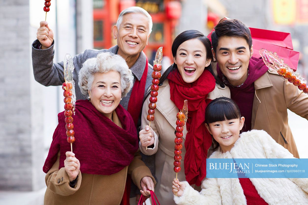 Cheerful Chinese family with candied haw berries celebrating Chinese New Year