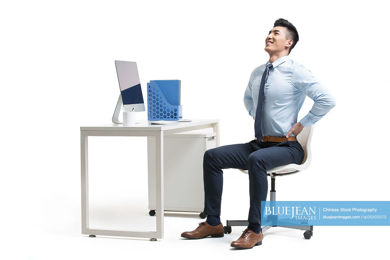 Young Chinese businessman exercising in office