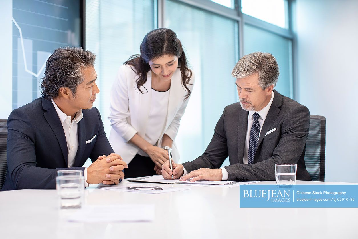 Business people signing contract in conference room