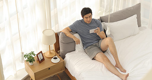 Happy young Chinese man playing mobile games in bedroom,4K