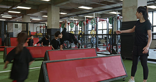 Active Chinese children having exercise class with their coach in gym,4K