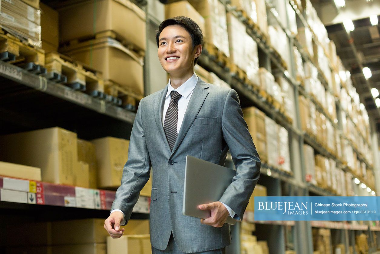 Happy Chinese businessman on the move in warehouse