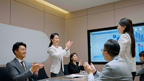 Cheerful Chinese business people applauding in meeting room