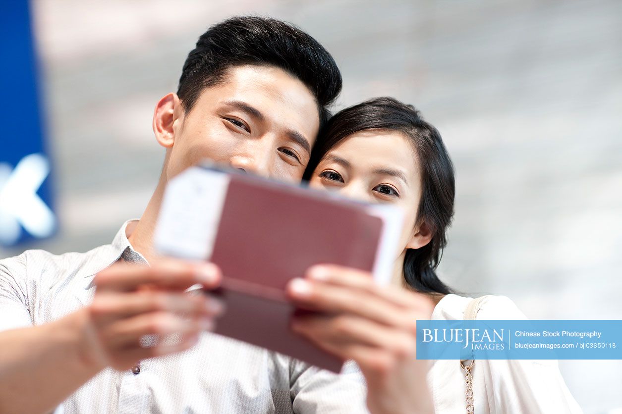 Young Chinese couple at the airport with flight tickets and passports