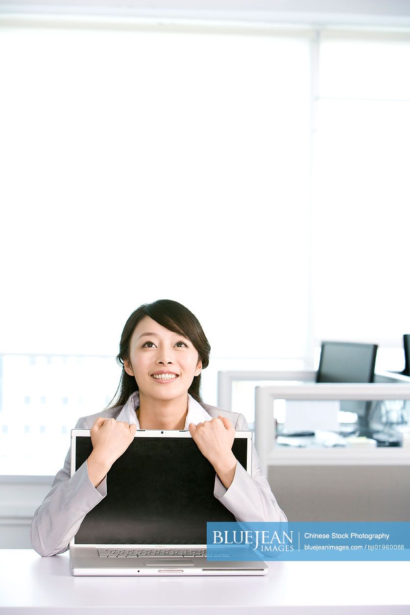 Chinese office worker hugging her computer