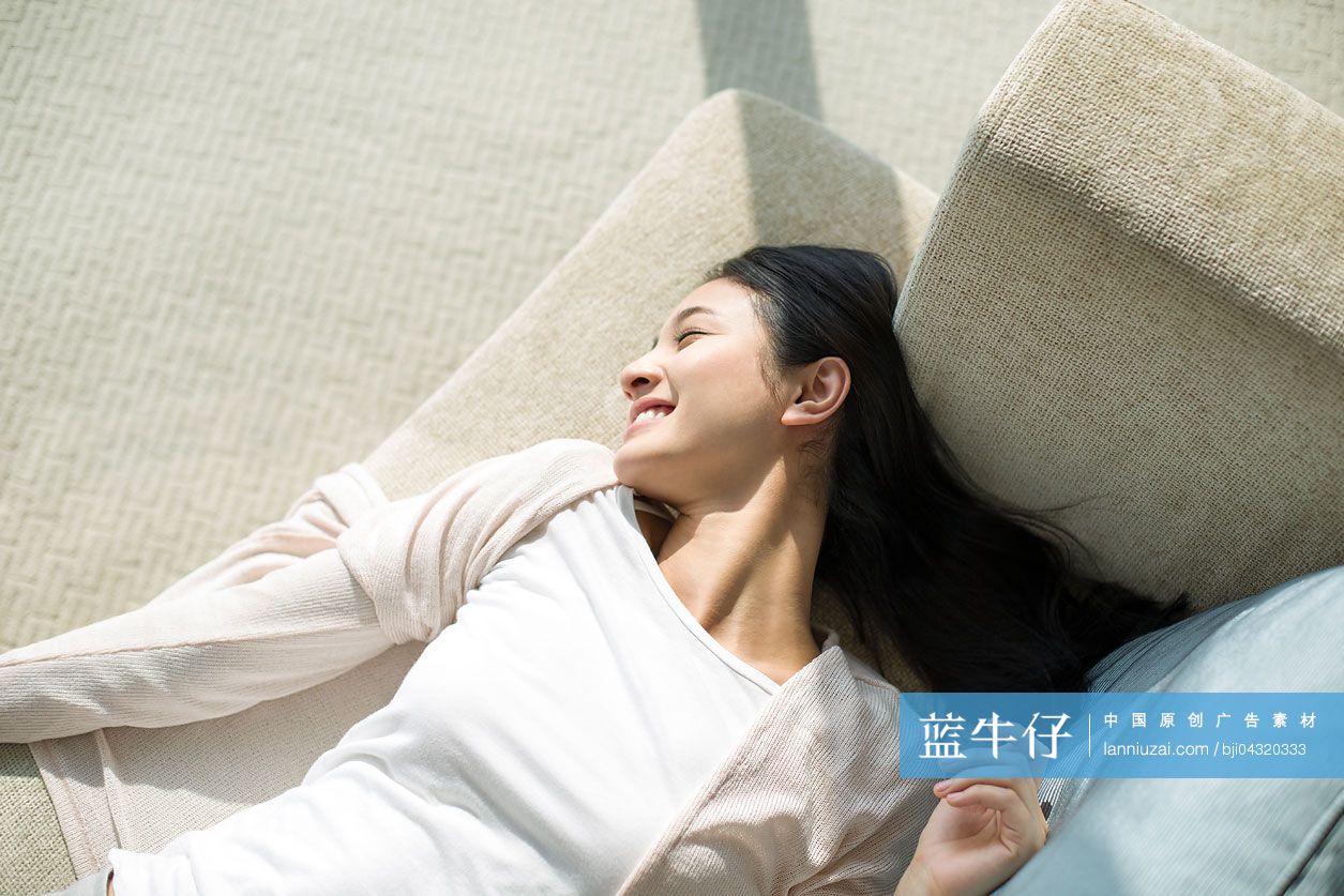 快乐的年轻女子躺在沙发上
