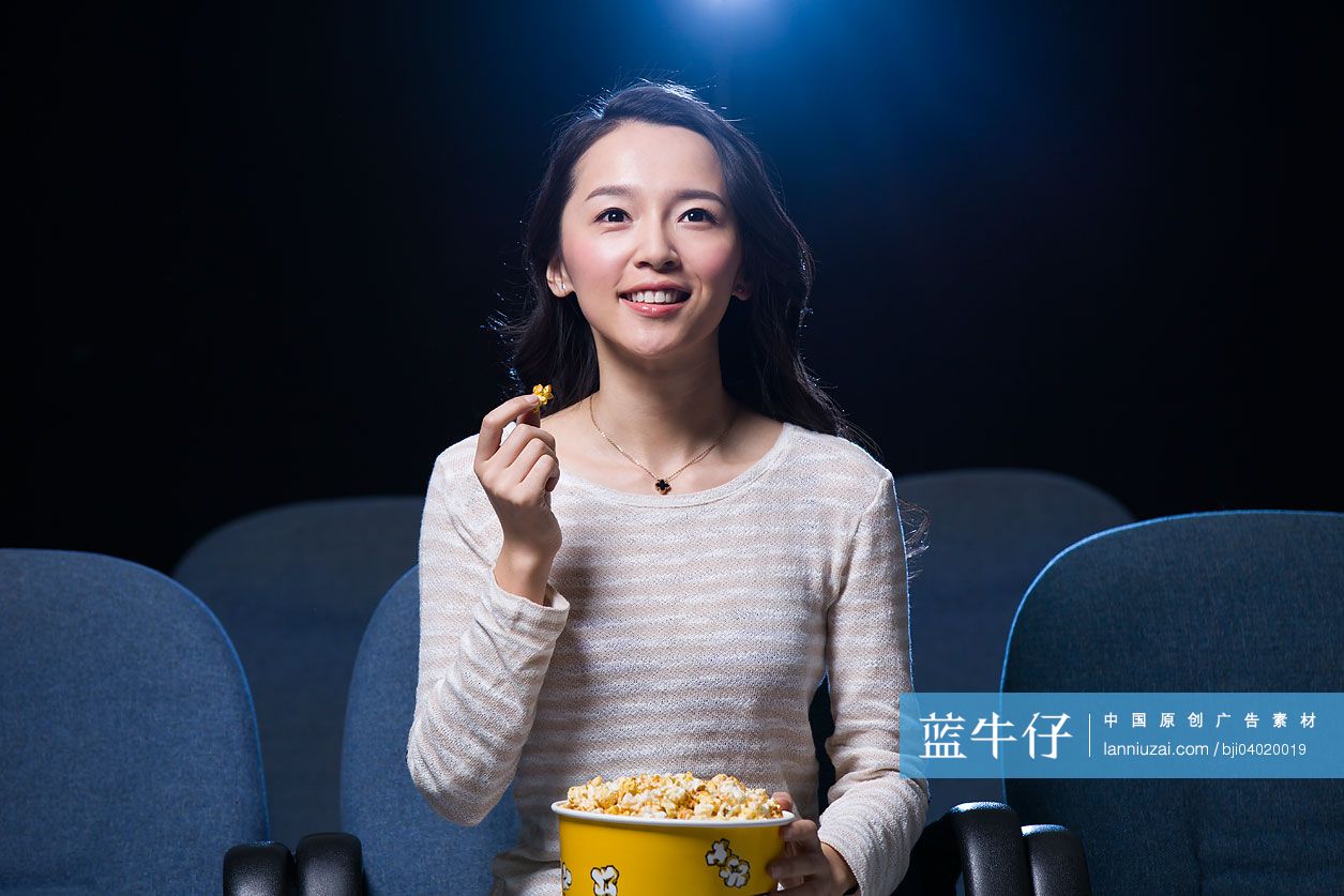 年轻女子边看电影边吃爆米花