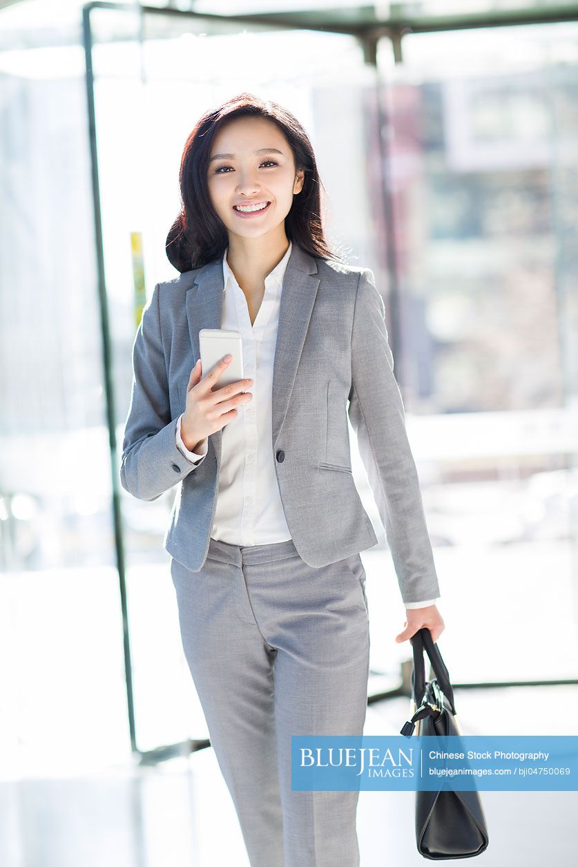 Chinese businesswoman holding a smart phone walking
