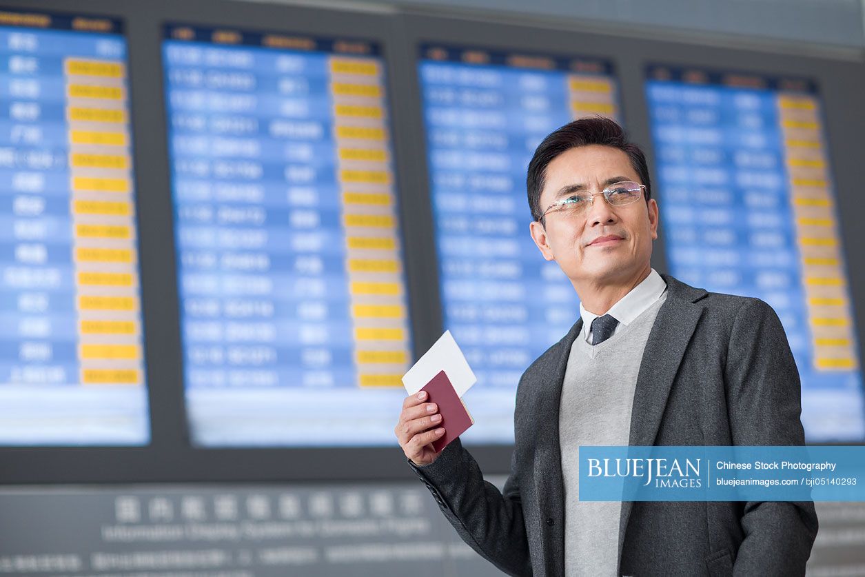 Chinese businessman with passport and airplane ticket