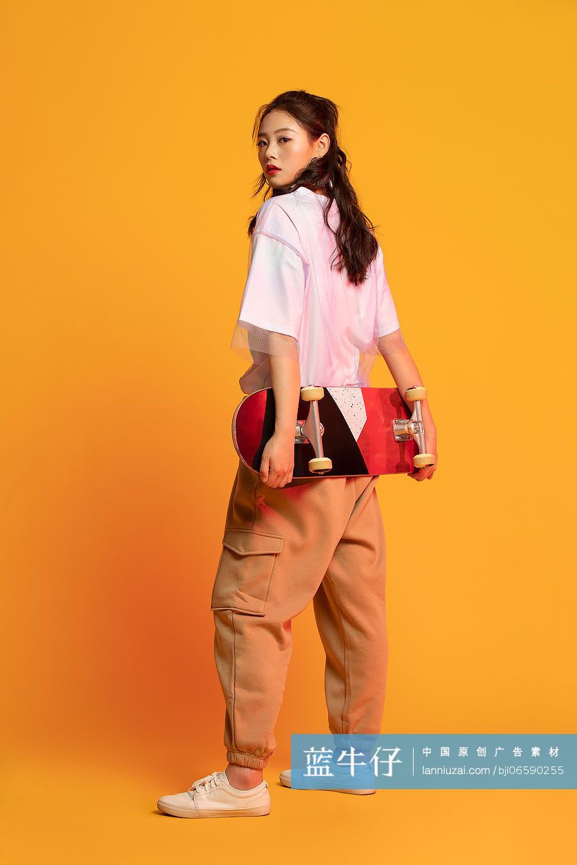 时尚的年轻女孩拿着滑板