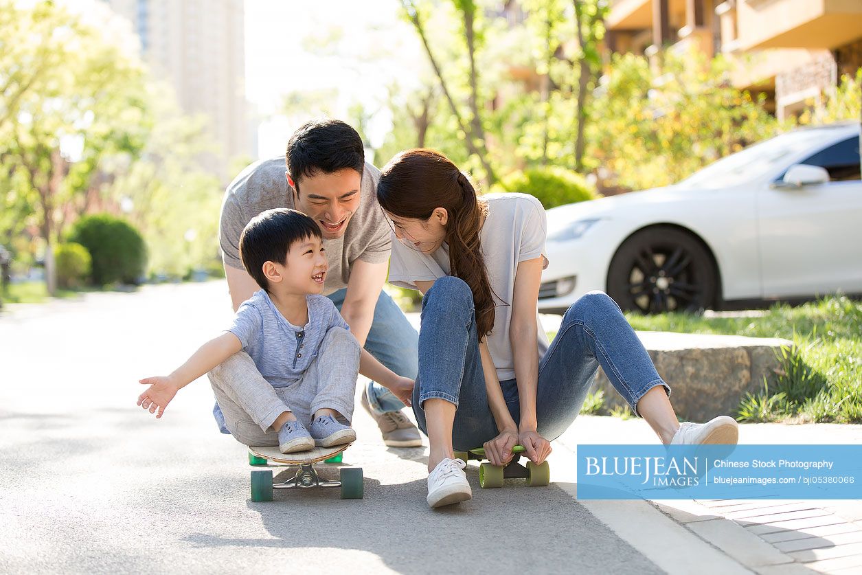 Happy young Chinese family playing with skateboards