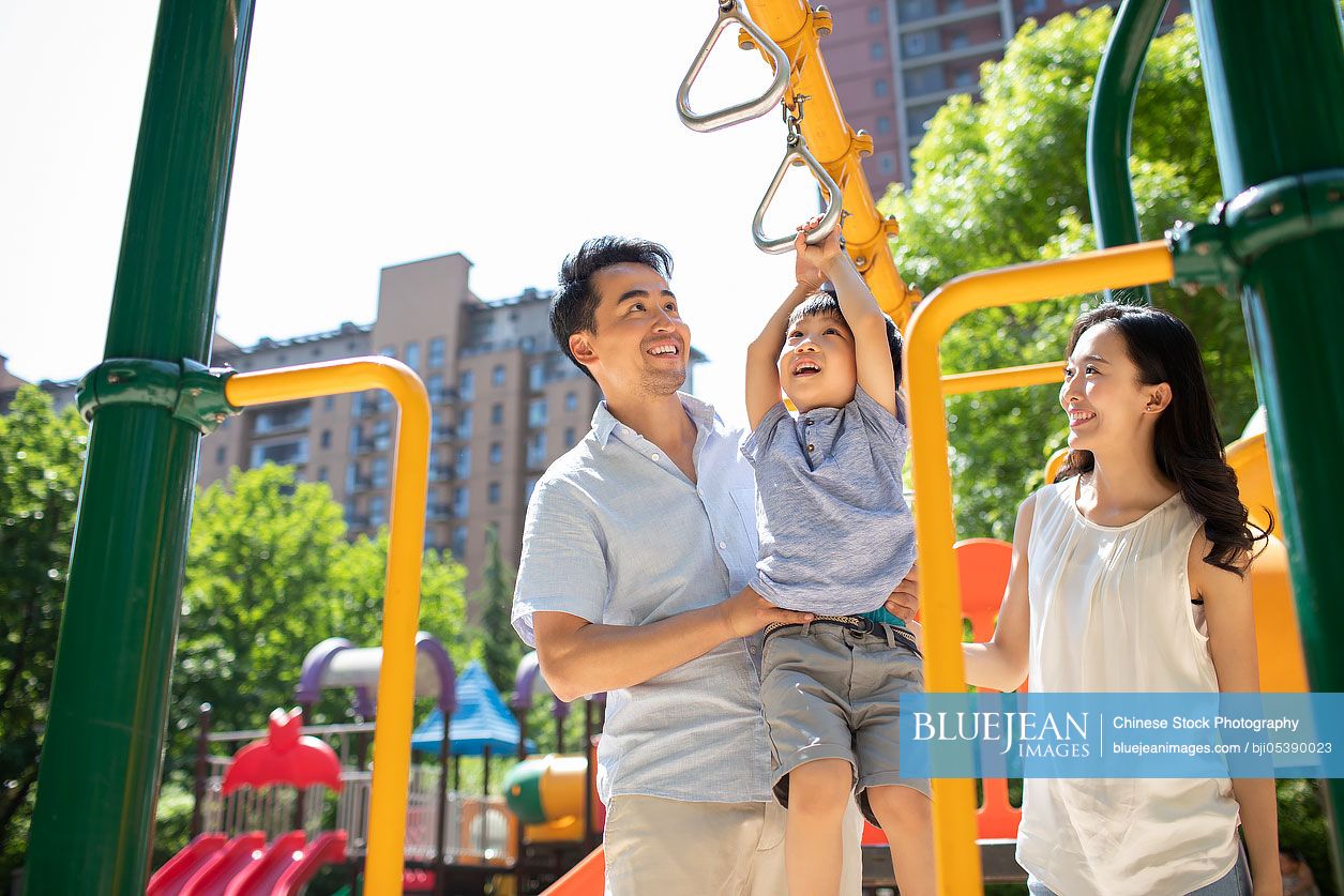 Happy young Chinese family playing in amusement park