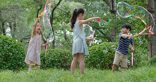 Three Chinese children blowing bubbles on grass,4K