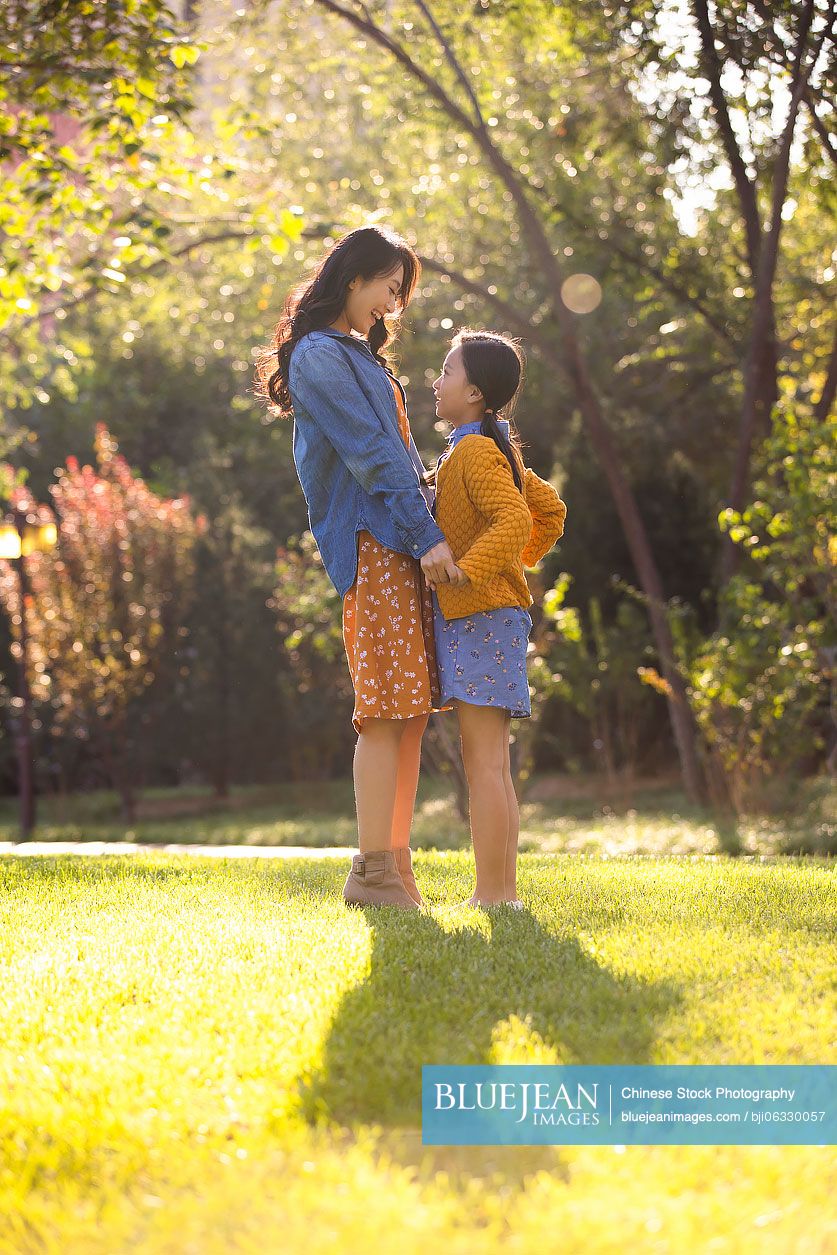 Happy Chinese mother and daughter having fun in park