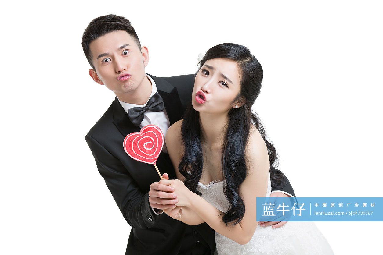 快乐的新娘和新郎拿着心型棒棒糖