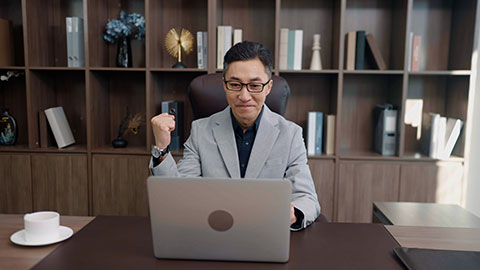 Successful Chinese businessman using laptop in office