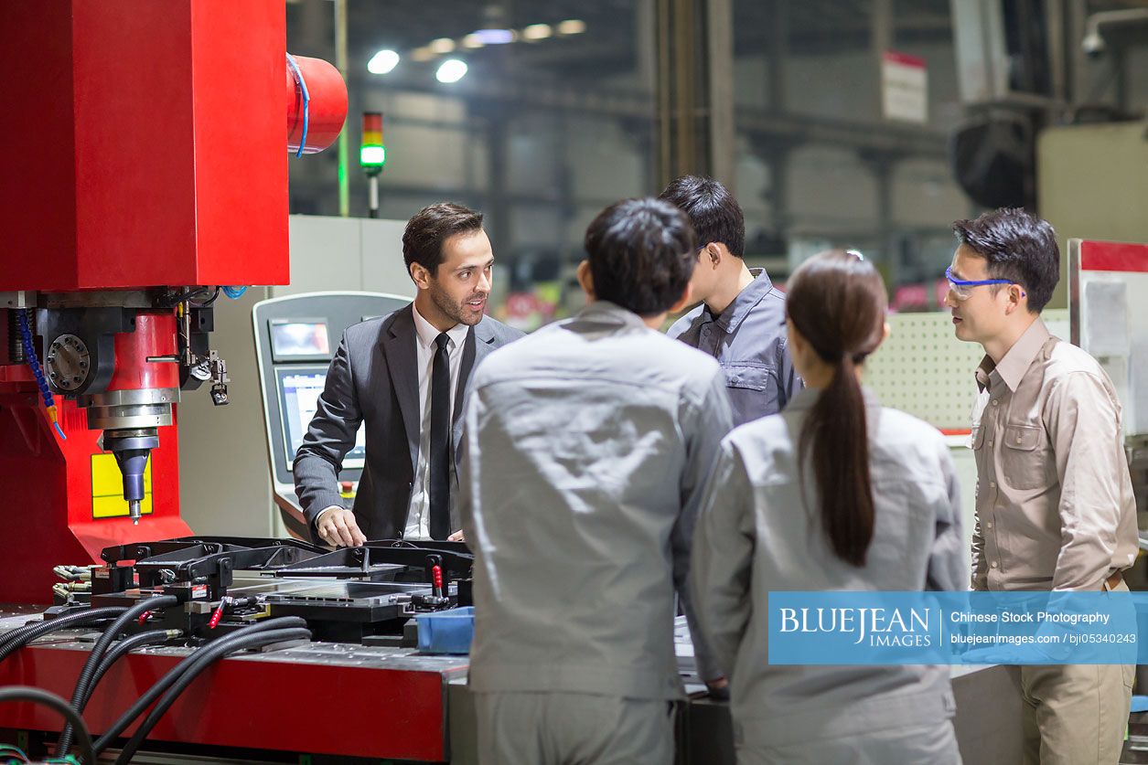 Businessman and engineers checking machine in the factory